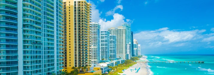 Chiropractic Service Area Miami FL city overview Oceanfront high-rise buildings along the beach in Miami, Florida, with turquoise waters and a clear blue sky.
